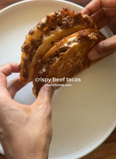 Crispy ground beef tacos with fresh toppings on a wooden table