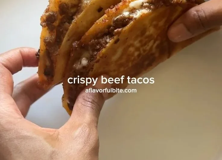 Crispy ground beef tacos with fresh toppings on a wooden table