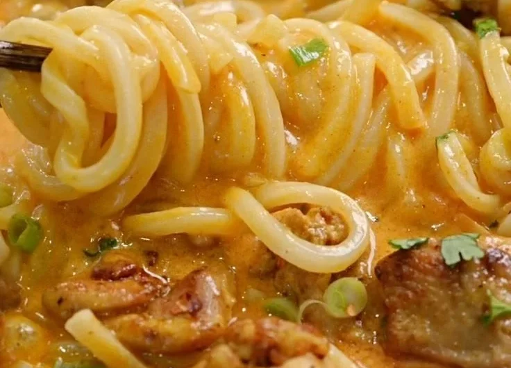 Bowl of Thai-inspired coconut red curry chicken udon with vibrant vegetables