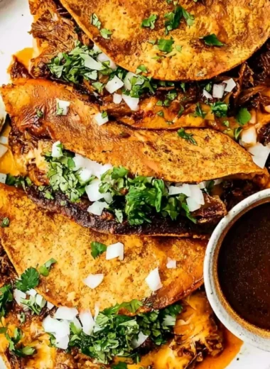 Delicious Beef Birria Tacos topped with cheese and garnished with cilantro and onions.