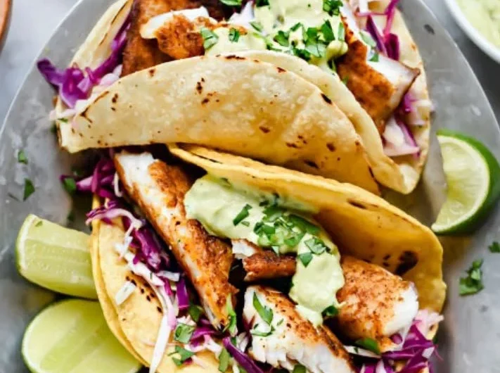Delicious blackened fish tacos with avocado cream sauce on a plate