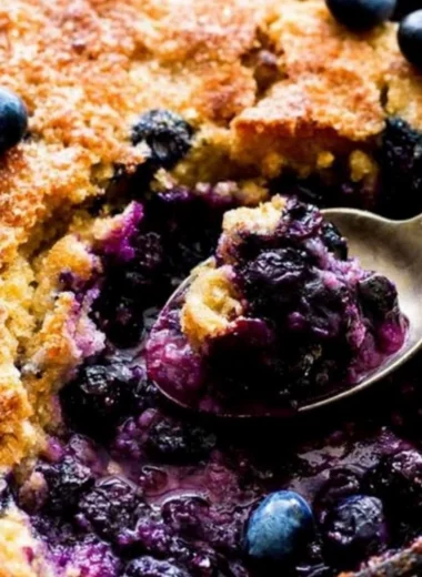 Homemade blueberry cobbler topped with golden crust and fresh berries