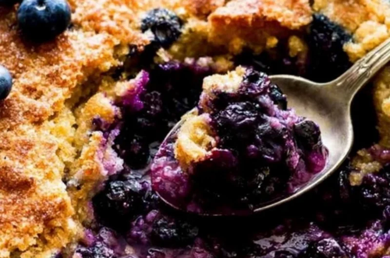 Homemade blueberry cobbler topped with golden crust and fresh berries