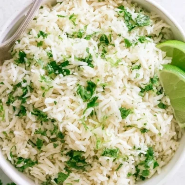 Bowl of cilantro lime rice garnished with fresh cilantro and lime wedges