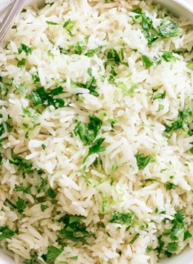 Bowl of cilantro lime rice garnished with fresh cilantro and lime wedges