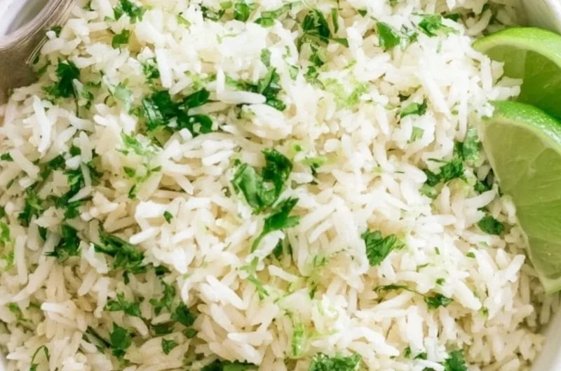 Bowl of cilantro lime rice garnished with fresh cilantro and lime wedges