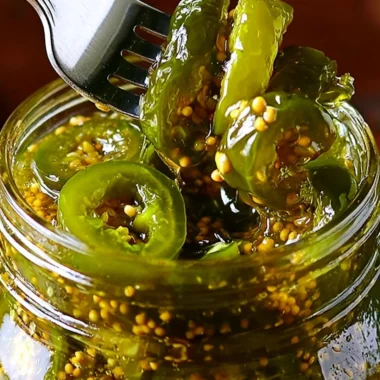 Jars of homemade cowboy candy with jalapeños and sugary syrup