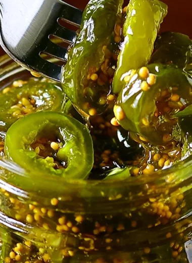 Jars of homemade cowboy candy with jalapeños and sugary syrup