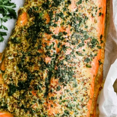Dijon baked salmon on a serving plate garnished with herbs