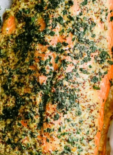 Dijon baked salmon on a serving plate garnished with herbs
