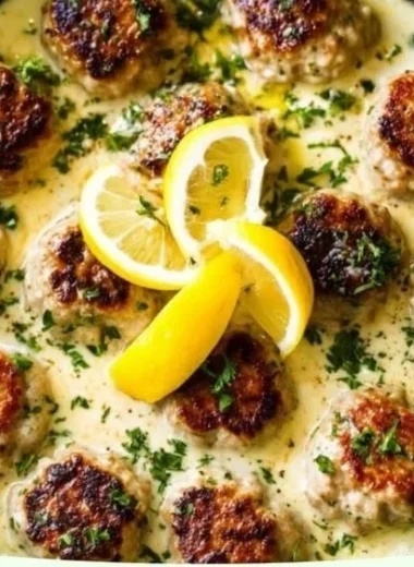 Plate of Greek chicken meatballs with lemon cream sauce garnished with herbs