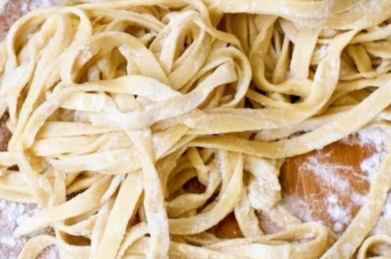 Freshly made homemade egg noodles on a wooden table