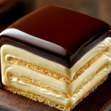 No-bake chocolate eclair cake topped with chocolate icing on a white plate.