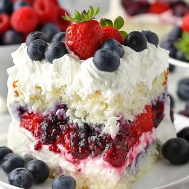 Delicious Summer Berry Poke Cake topped with fresh berries and whipped cream.