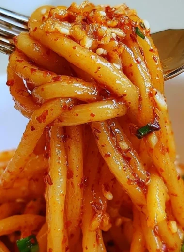 Bowl of cozy garlic chili oil noodles garnished with fresh herbs and peppers.