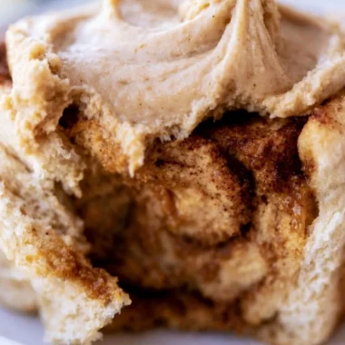 Cozy pumpkin butter cinnamon rolls topped with creamy frosting and spices.