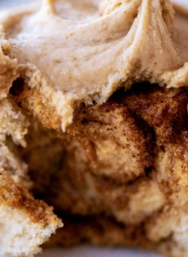 Cozy pumpkin butter cinnamon rolls topped with creamy frosting and spices.