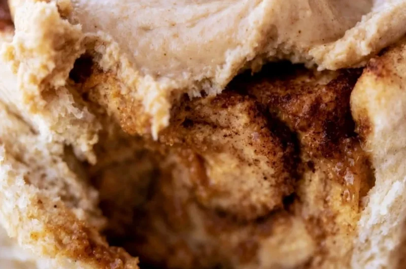 Cozy pumpkin butter cinnamon rolls topped with creamy frosting and spices.