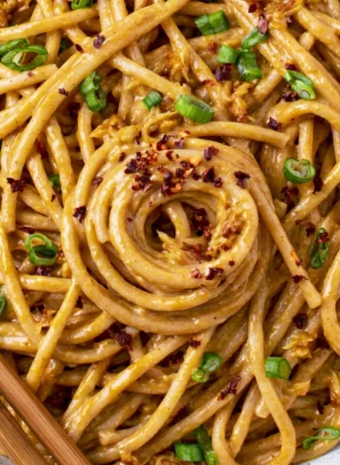 Plate of cozy vegan garlic noodles topped with fresh herbs and chili flakes.