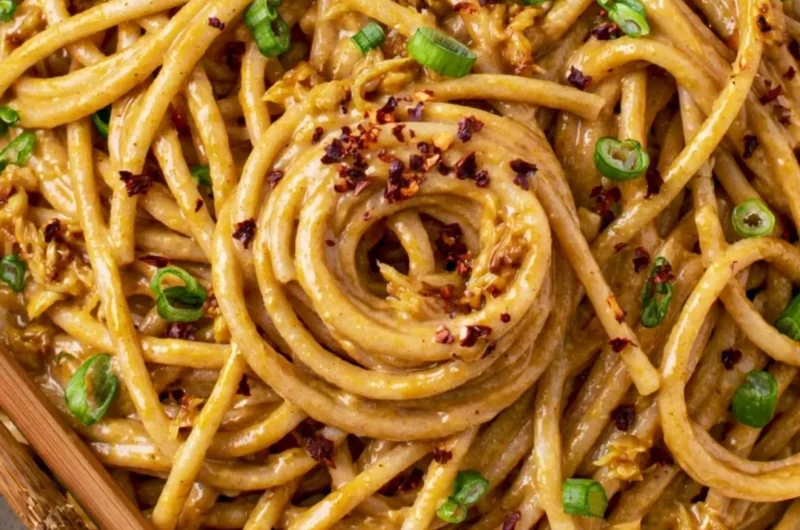 Plate of cozy vegan garlic noodles topped with fresh herbs and chili flakes.