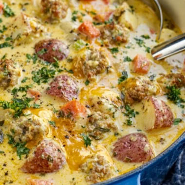 Bowl of creamy sausage potato soup garnished with herbs