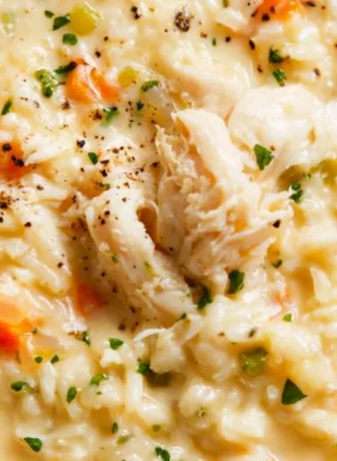 A bowl of creamy chicken rice soup garnished with herbs.