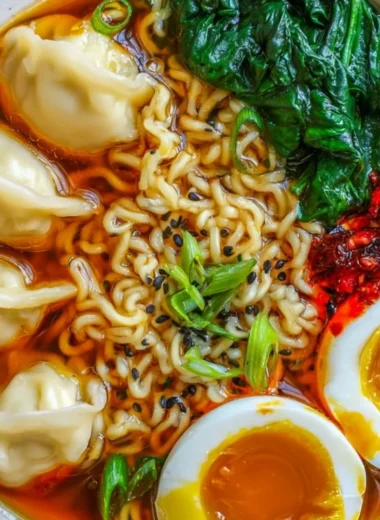 A steaming bowl of Dumpling Ramen topped with fresh herbs and vegetables