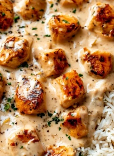 Creamy smothered chicken served with rice on a plate, a delicious comfort food dish.